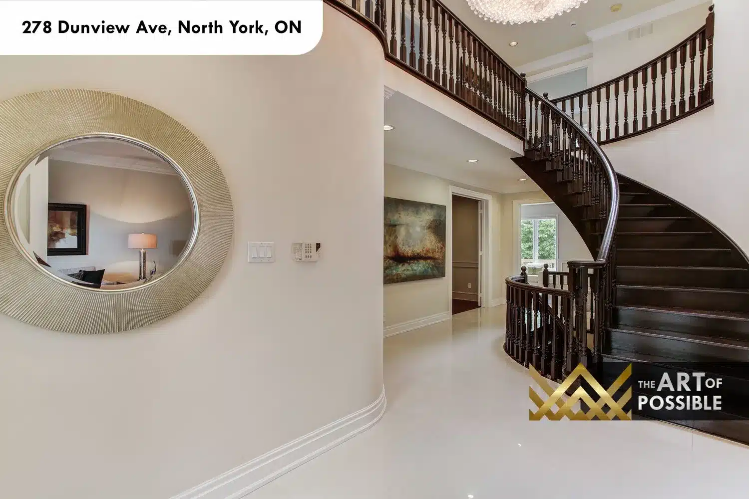Curved dark-stained staircase in the foyer with turned spindle balusters and crystal chandelier