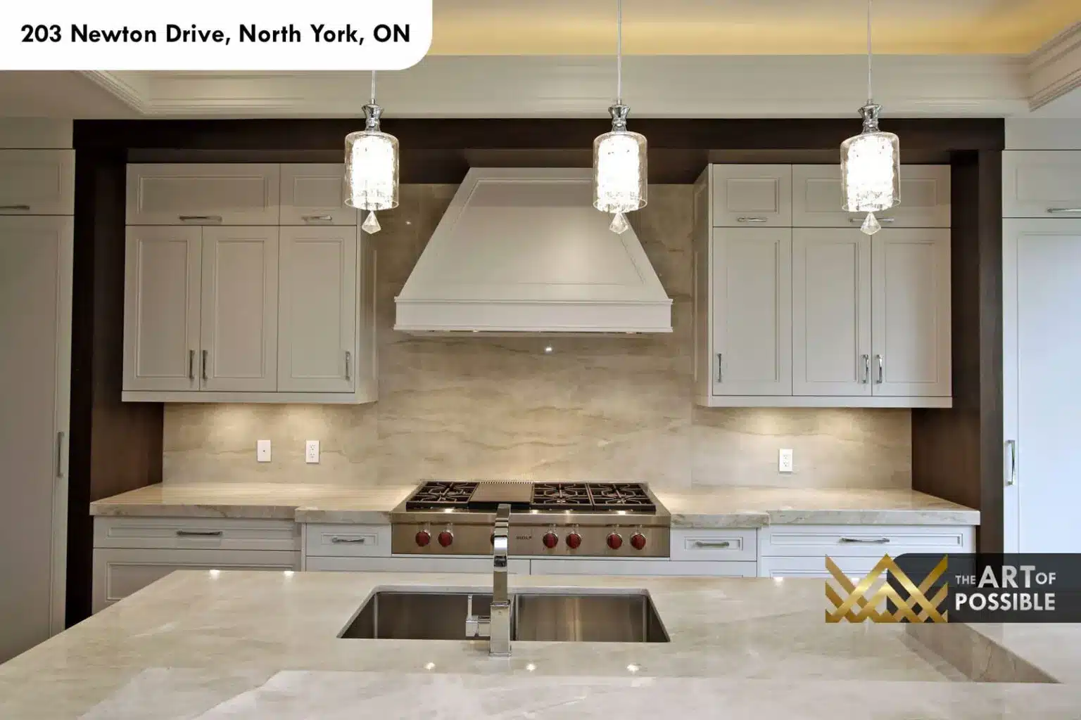 Kitchen with Wolf rangetop, white range hood and marble slab backsplash