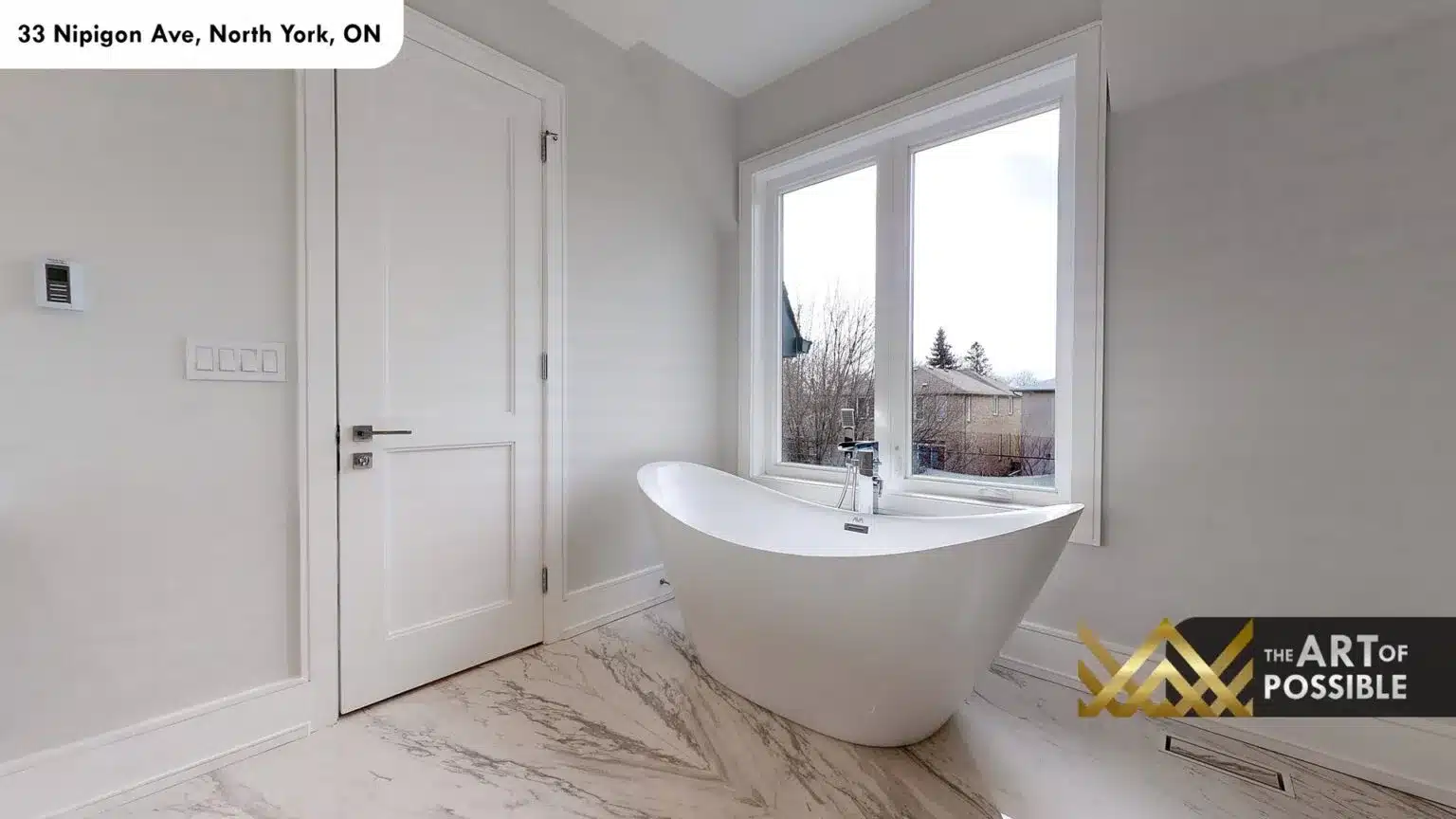 Freestanding white sculptural soaker tub at window in primary ensuite