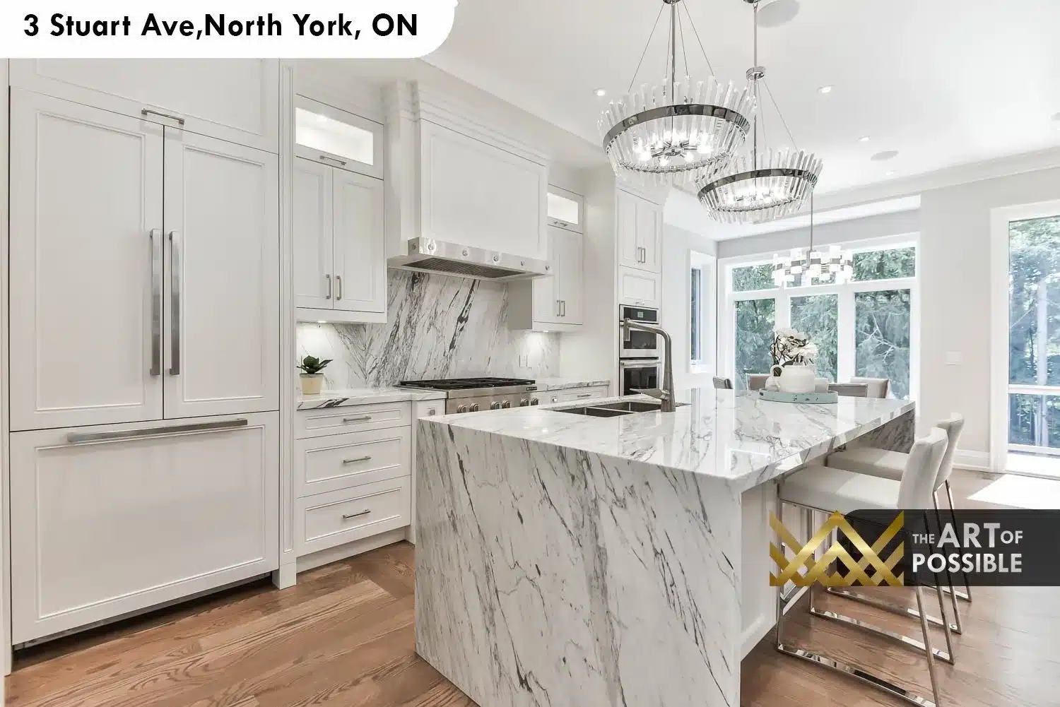 Kitchen with white shaker cabinetry, dramatic veined marble waterfall island and two-tier crystal drum chandeliers