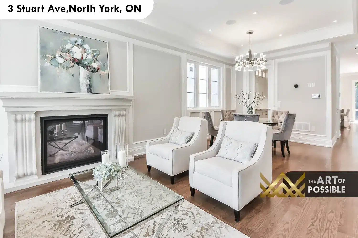 Living room open to dining area showing cylindrical glass chandelier, tray ceiling and white column pilasters