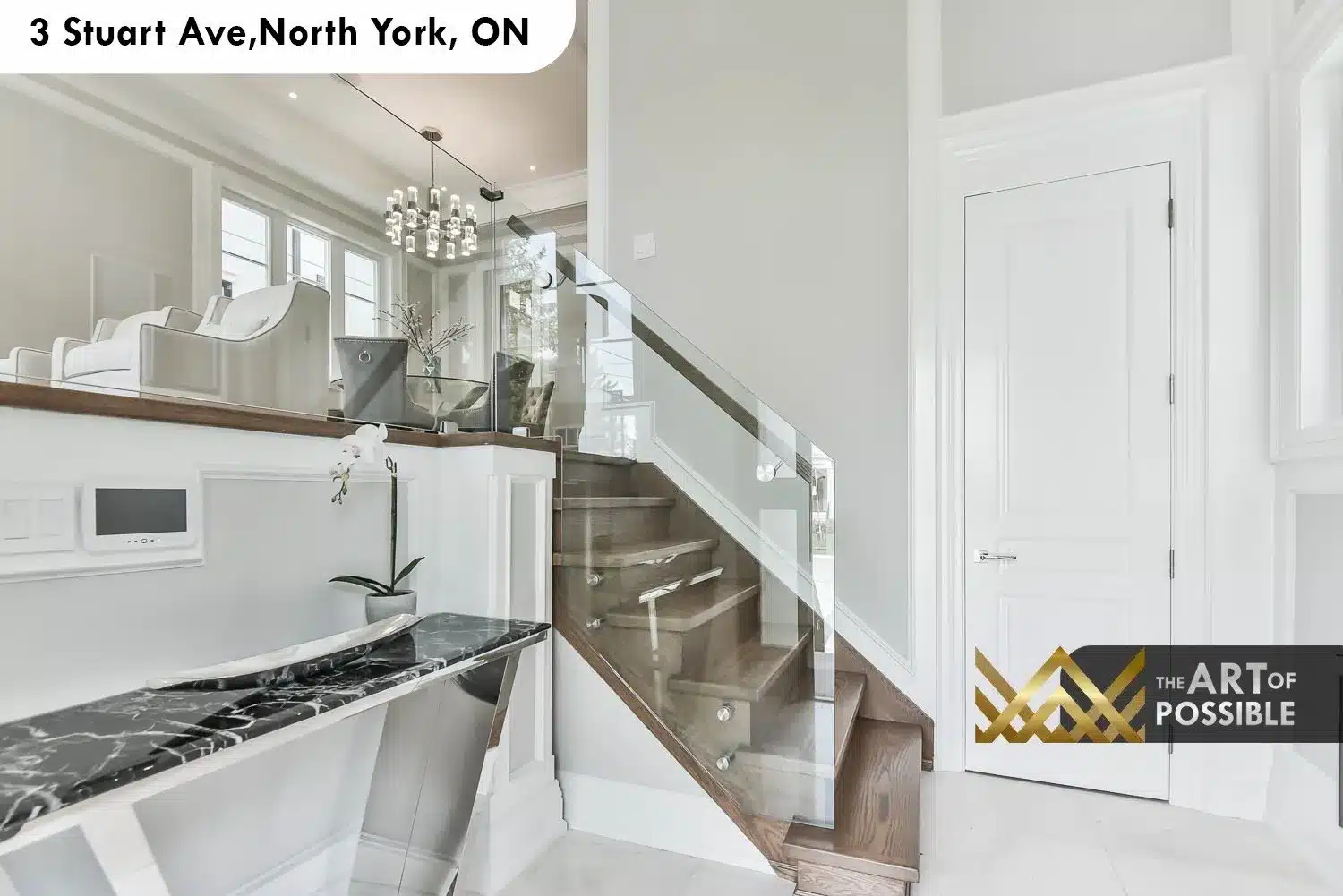 Foyer showing dark marble console table, glass panel staircase railing, and modern cylindrical chandelier beyond