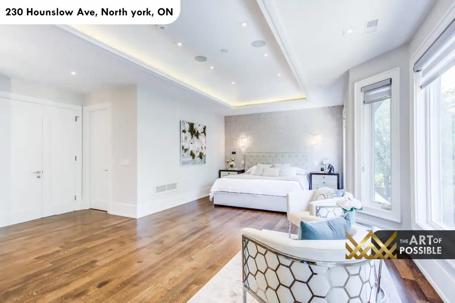 Primary bedroom with tufted headboard, tray ceiling and triple bay windows