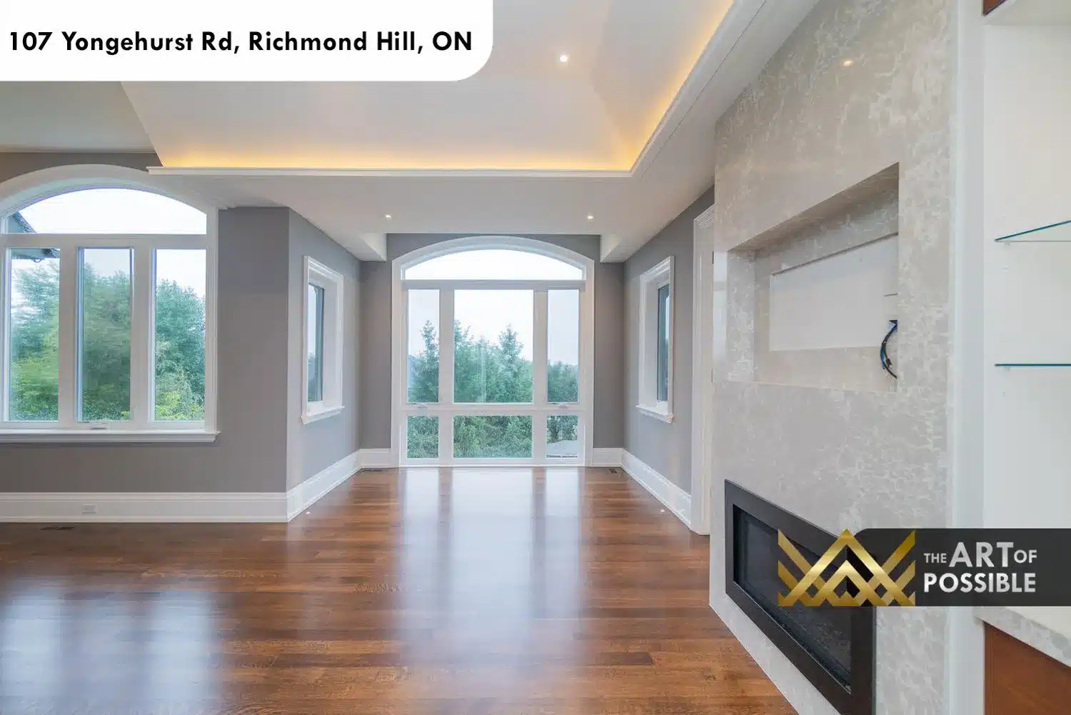 Primary suite with arched windows, LED cove ceiling and linear fireplace with textured stone surround