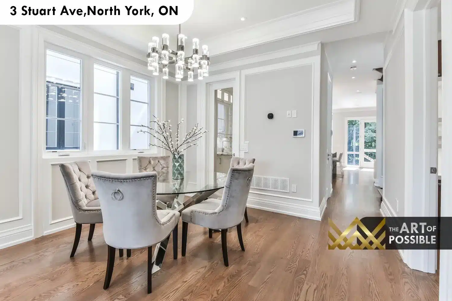 Dining room with cylindrical glass chandelier, tray ceiling, wainscoting and glass dining table