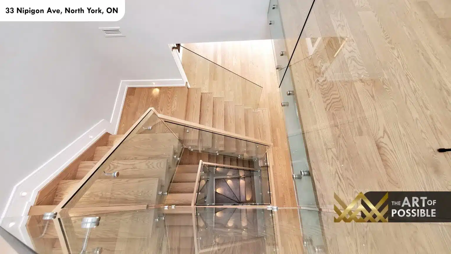 Overhead view down three-storey open-tread oak staircase with glass railings