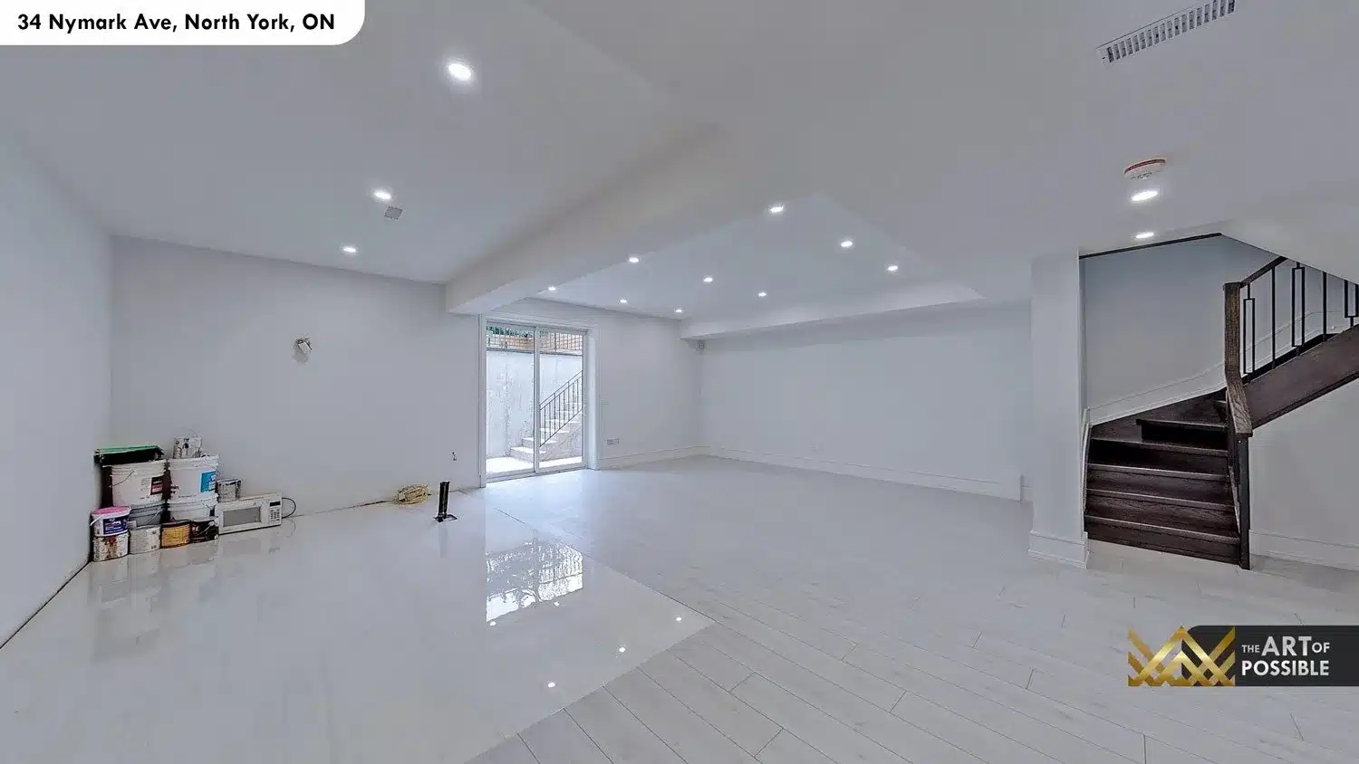 Lower level recreation room with polished white tile floors, coffered ceiling and walk-out sliding glass door