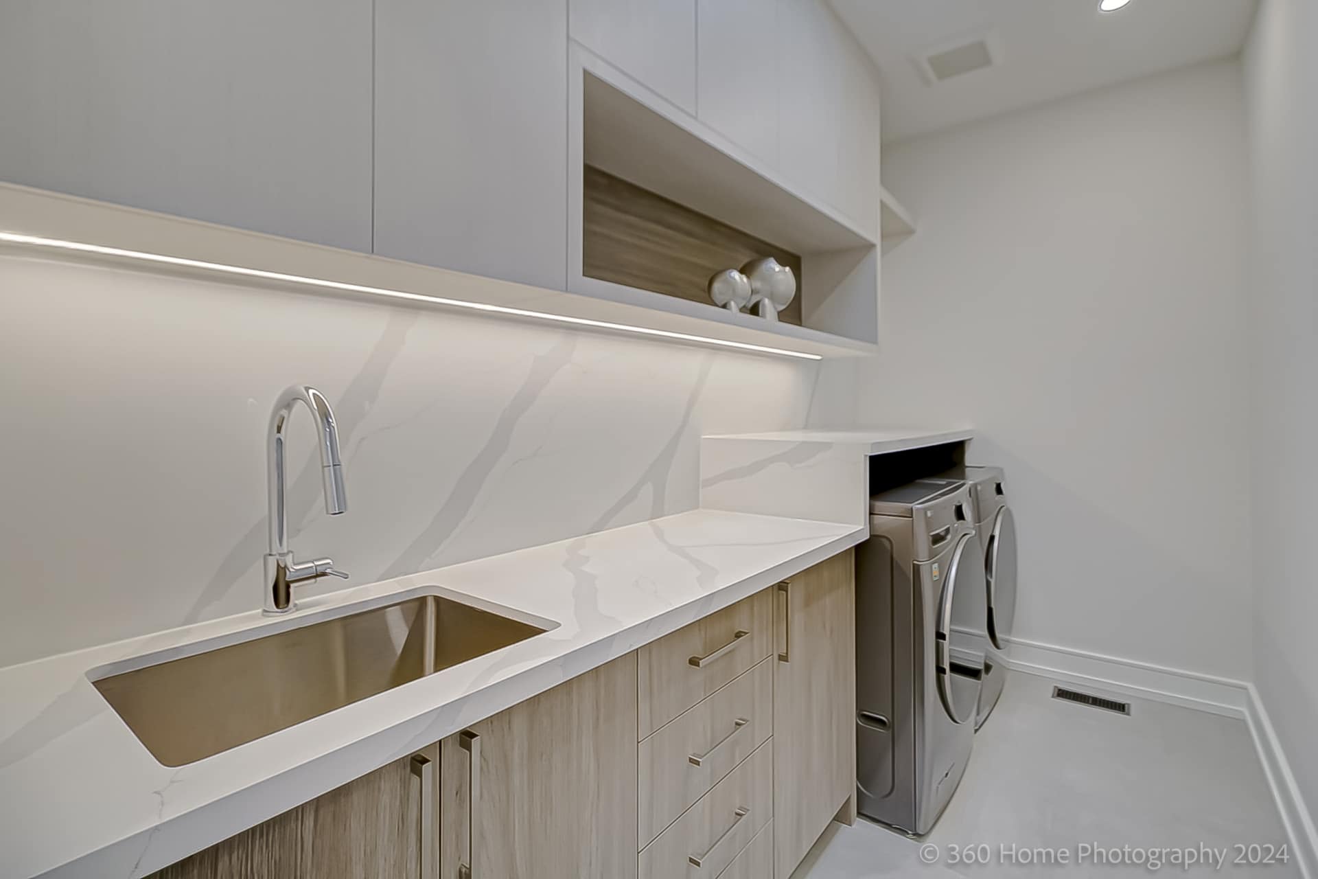 Upper floor laundry room with quartz counter, double sink and stainless washer dryer at 100 Glenvale Blvd