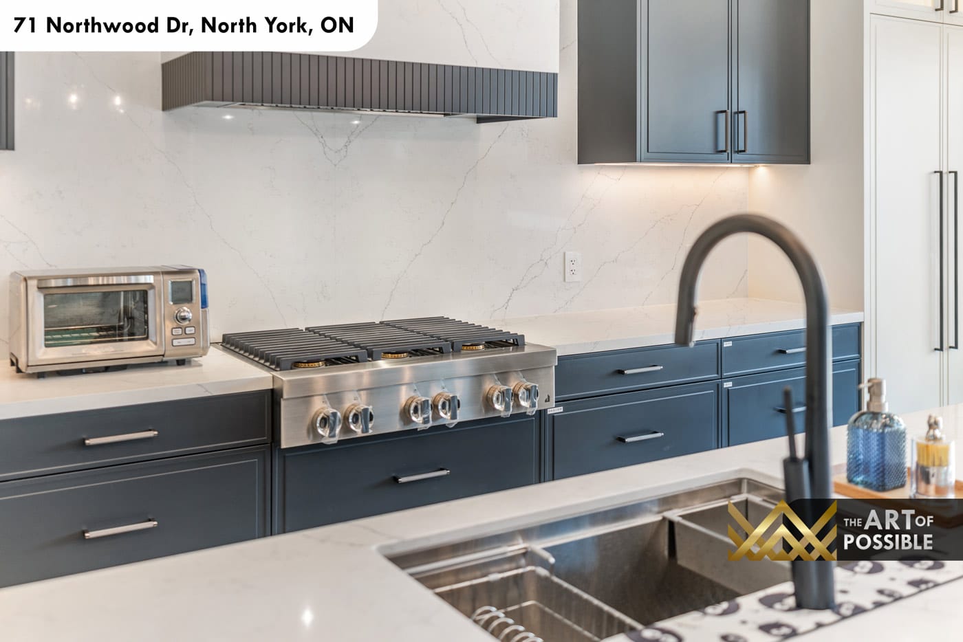 Kitchen cooktop detail showing 6-burner professional range, dark fluted hood and Calacatta marble backsplash