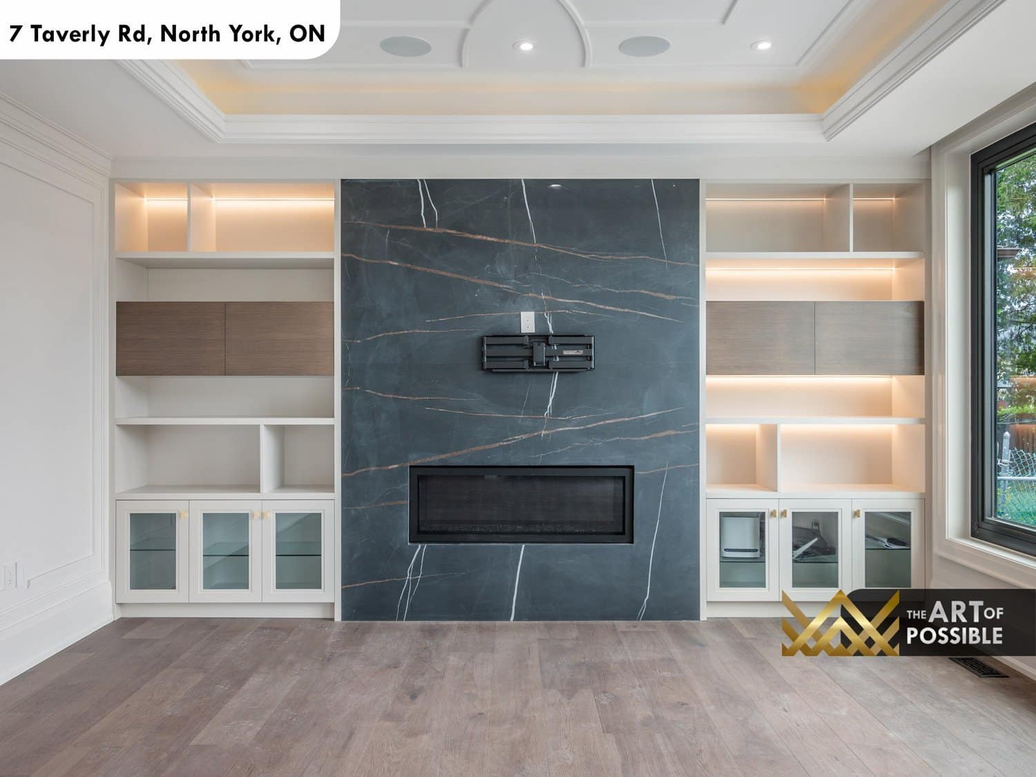 Family room fireplace wall in dark marble with flanking LED-lit built-in shelving