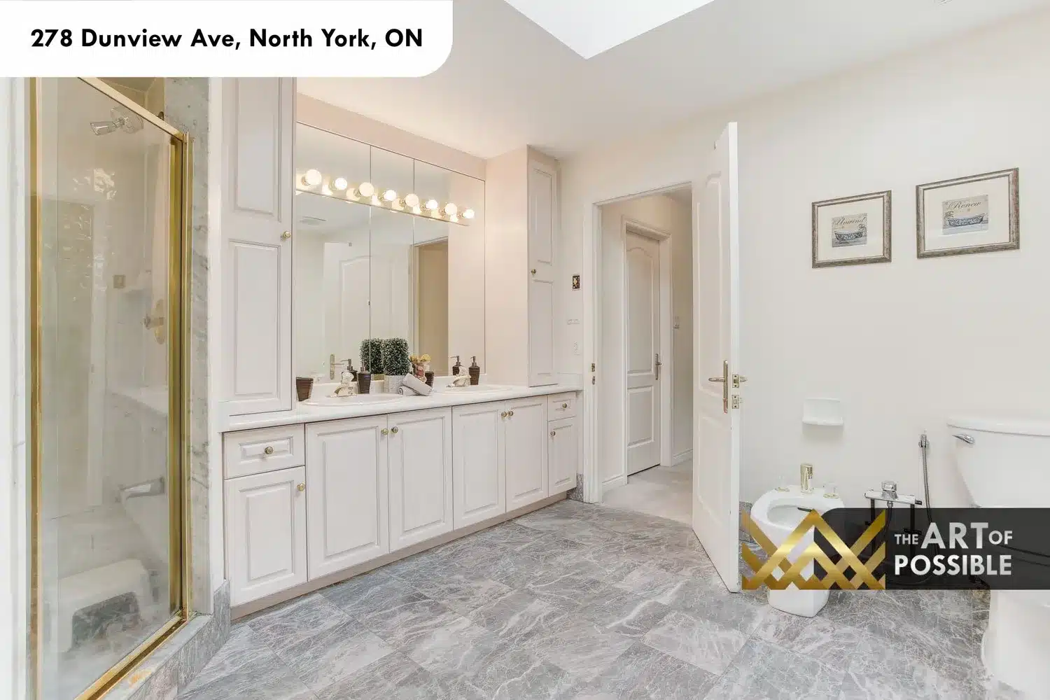 Primary ensuite dual vanity with white cabinetry, brass pulls and grey marble tile floors