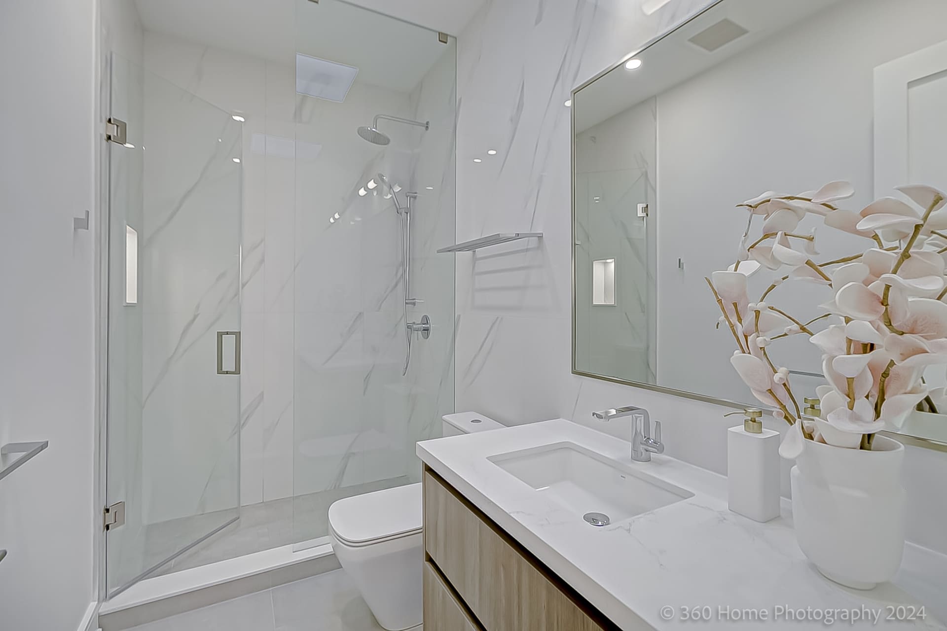 Secondary ensuite with marble tile walls, glass shower and floating oak vanity at 100 Glenvale Blvd