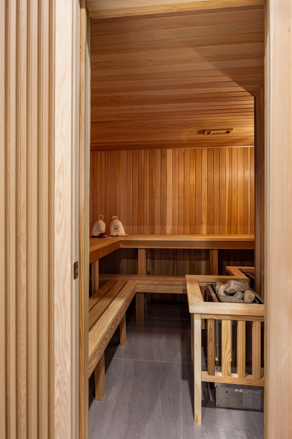 Full cedar sauna at 27 Farr Ave with tongue-and-groove cedar walls, multi-level benches and rock heater