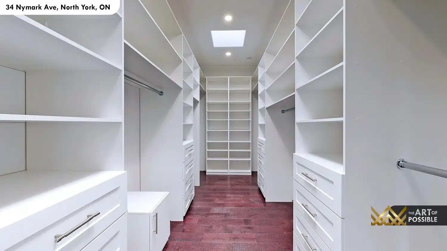 Primary walk-in closet with skylight - custom white built-in cabinetry with shelves, hanging rods and drawers