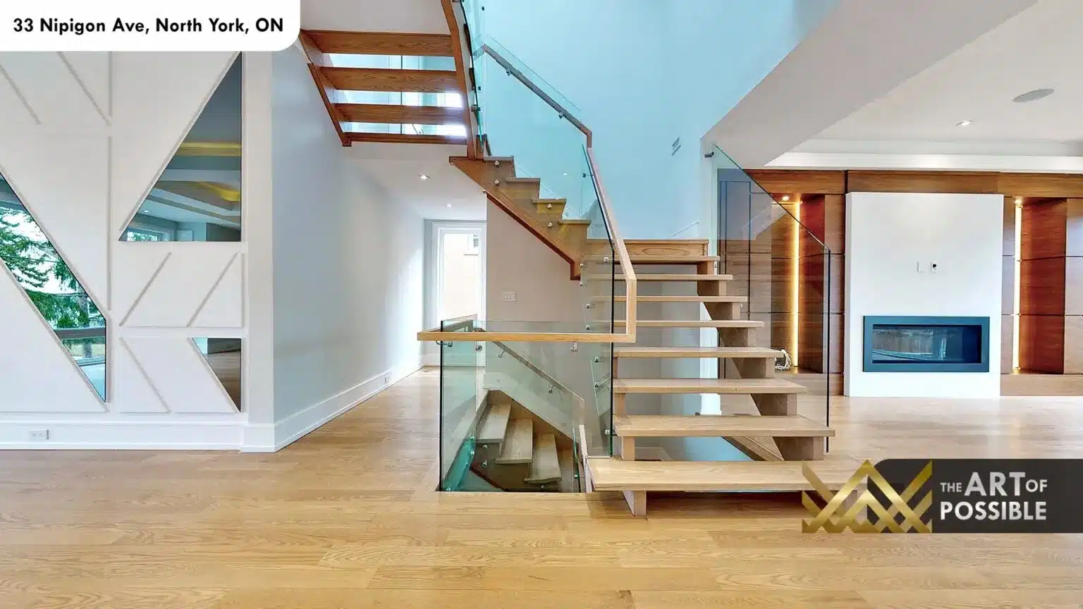Open-tread oak staircase with glass railings viewed from main floor