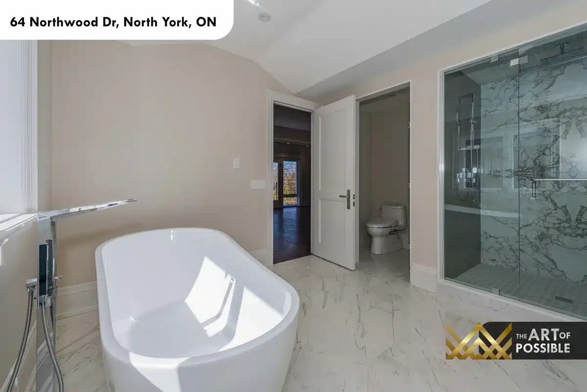 Walk-in glass shower with marble tile walls in primary ensuite