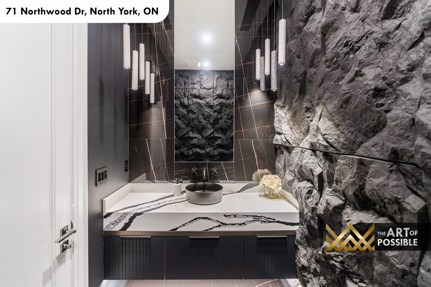 Powder room with rough-cut natural stone feature wall and dark marble tile surround
