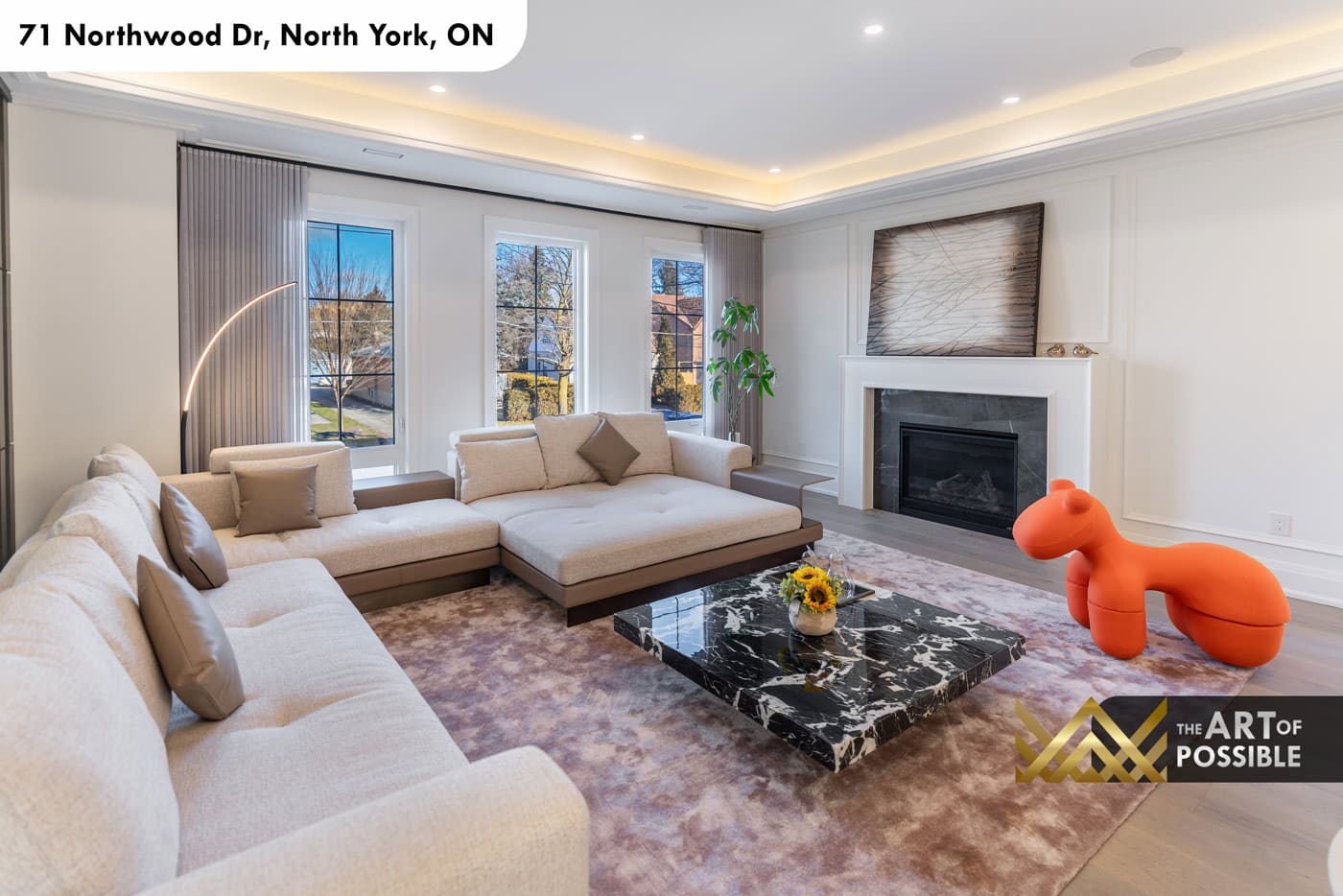 Living area showing fireplace with dark marble insert, linen sectional sofa and black-frame grid windows