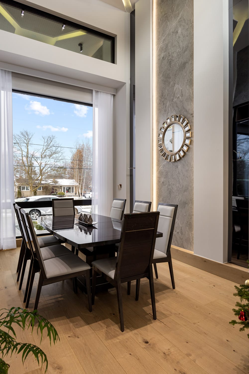 Dining room at 27 Farr Ave with floor-to-ceiling windows, grey marble LED-lit accent column and soaring ceilings