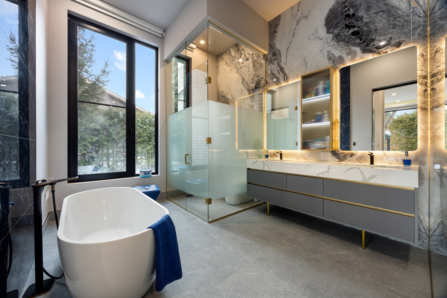 Primary ensuite at 27 Farr Ave with freestanding soaker tub, full book-matched marble walls, double vanity and frameless glass shower
