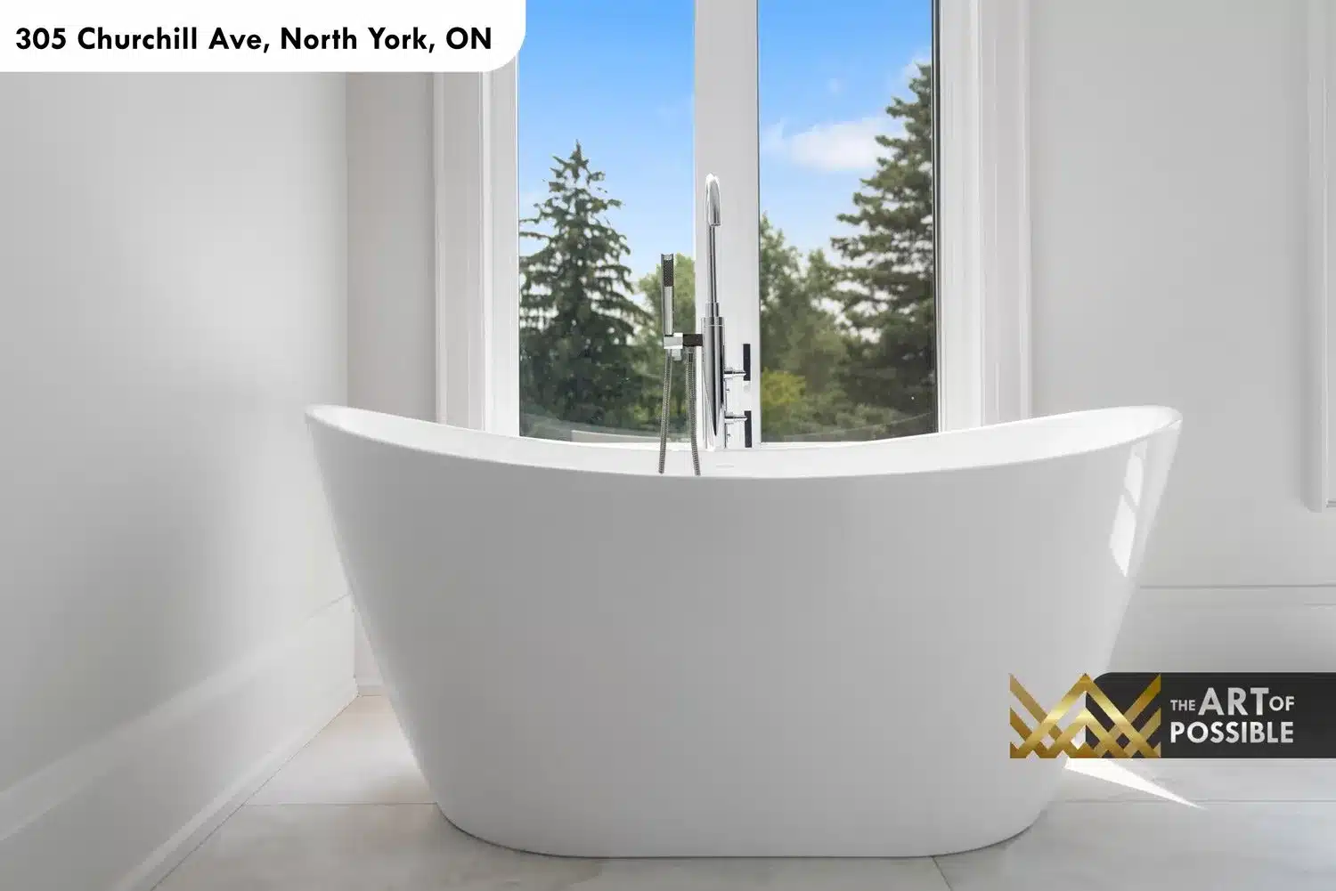 Close view of freestanding soaker tub with chrome floor-mounted filler and pine tree window backdrop
