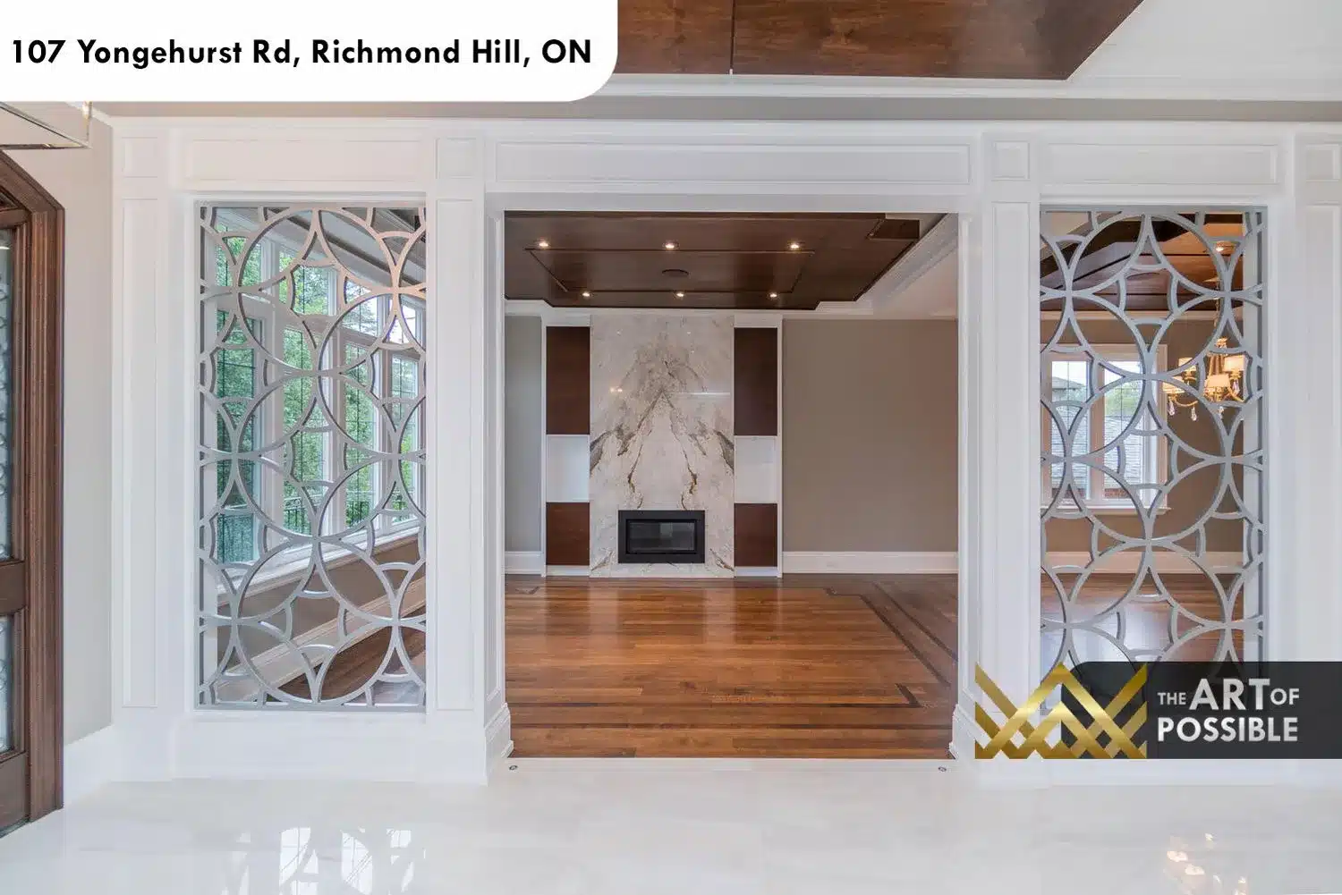 Formal living room entry framed by geometric laser-cut screen columns with marble fireplace beyond