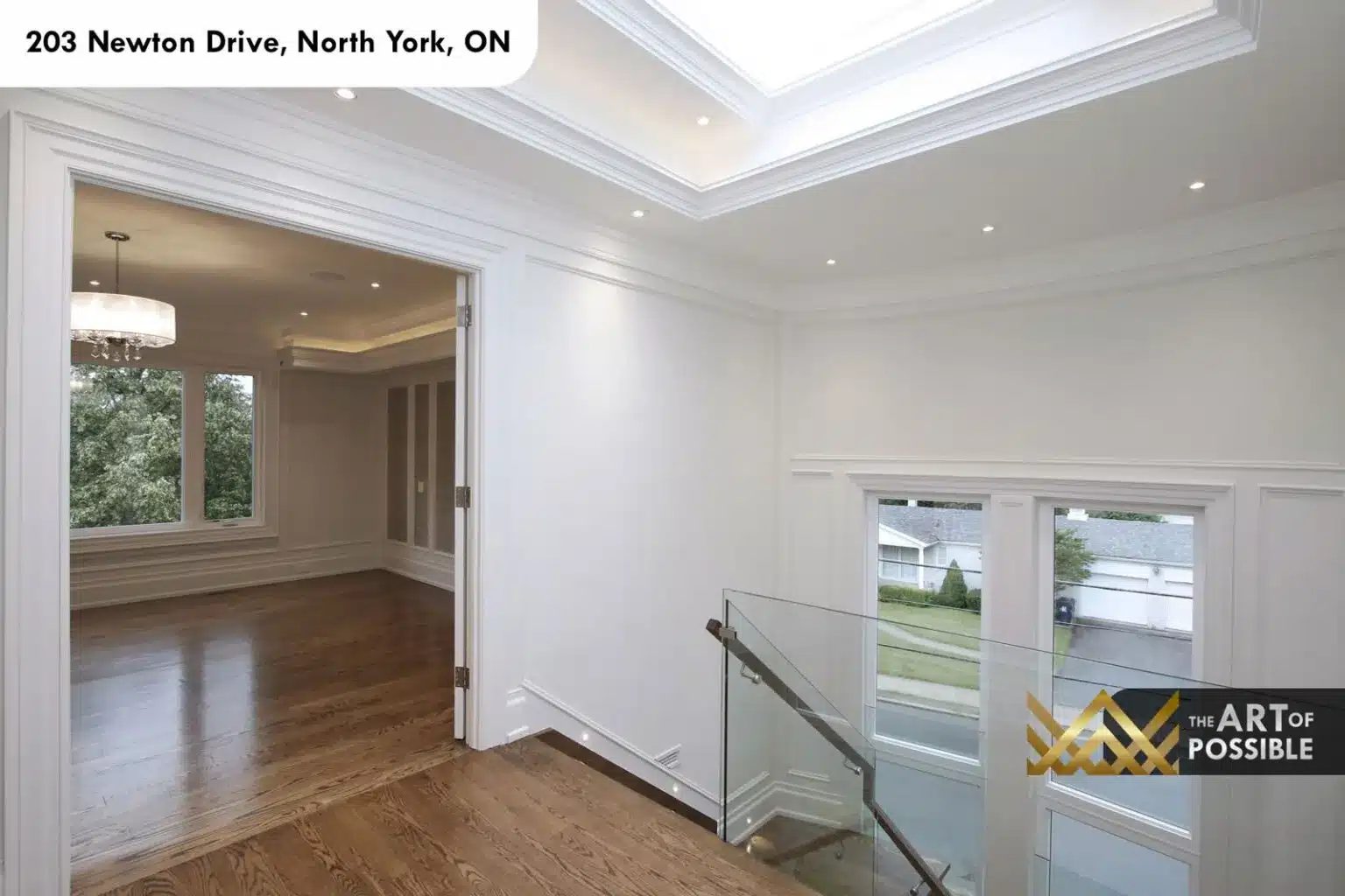 Skylit upper landing with glass railing overlooking the foyer