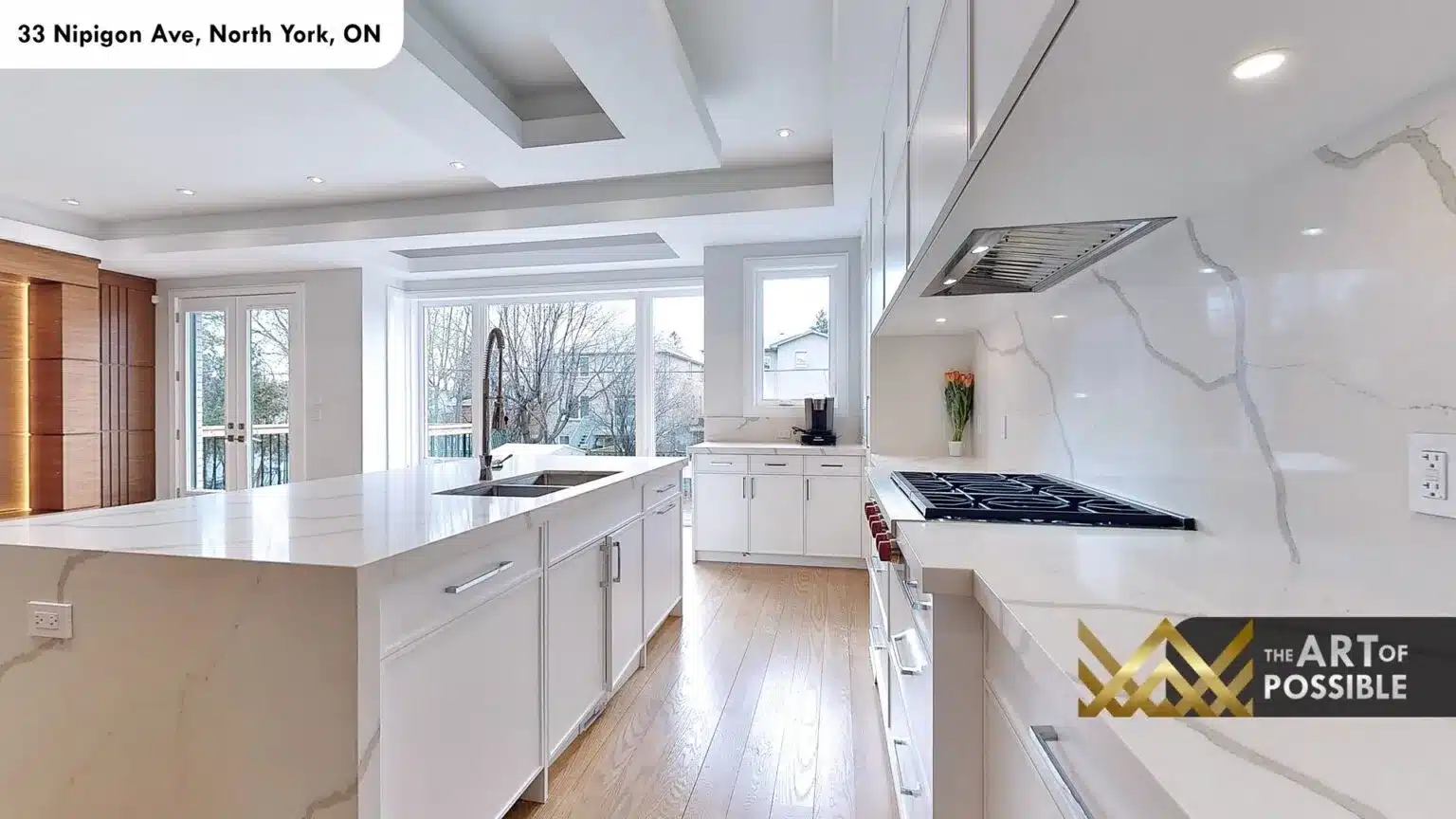 Kitchen viewed from island showing gas range and full-height quartz slab backsplash