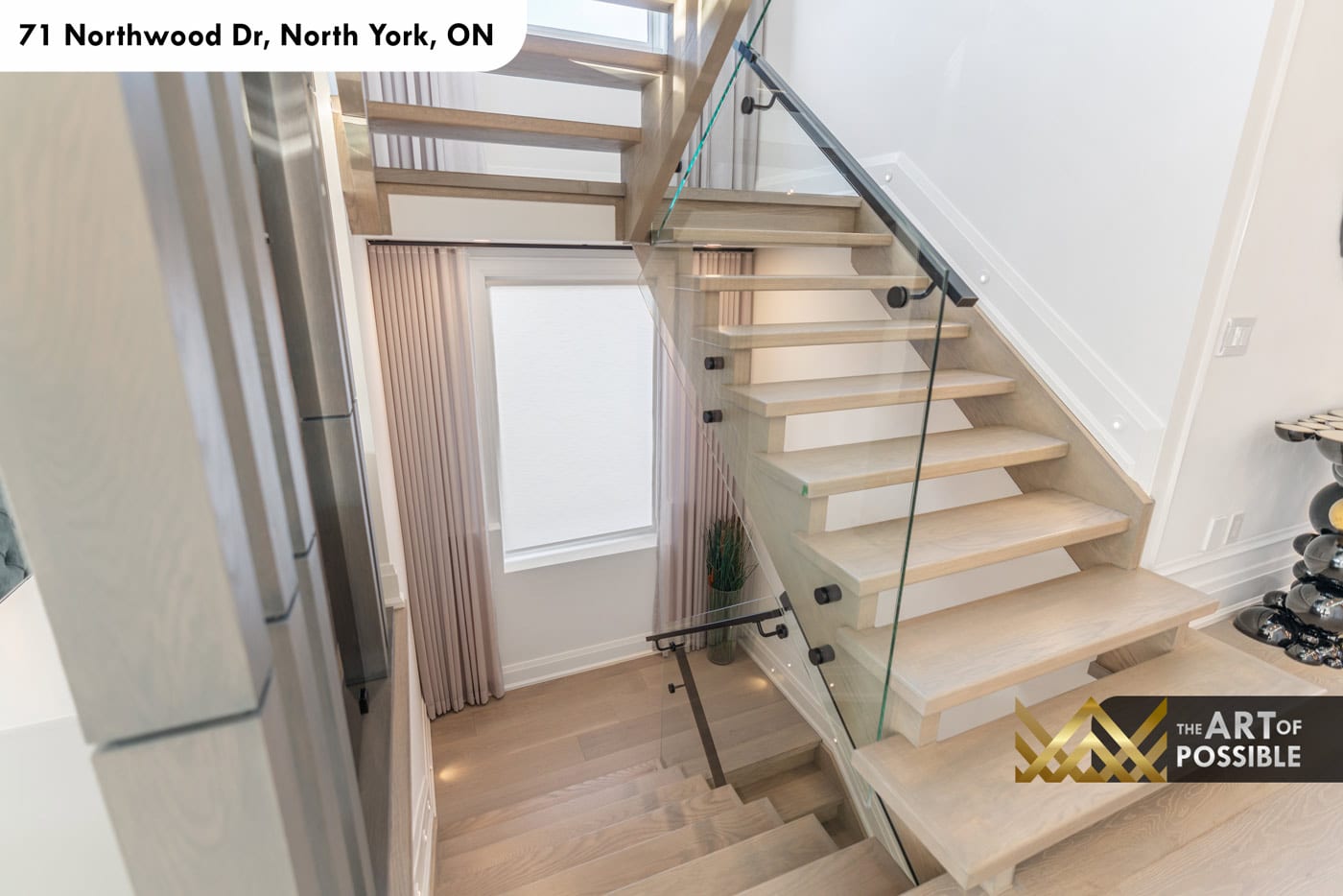 Staircase from above showing open oak treads, glass railings and natural light from landing window