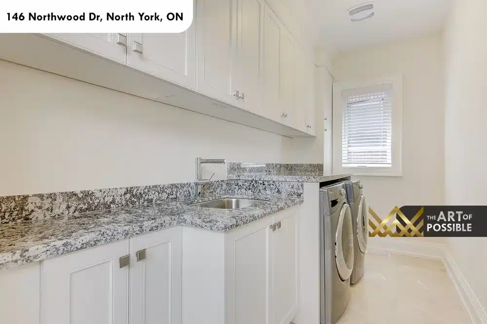 Upper laundry room with white cabinetry, granite counter and front-load machines