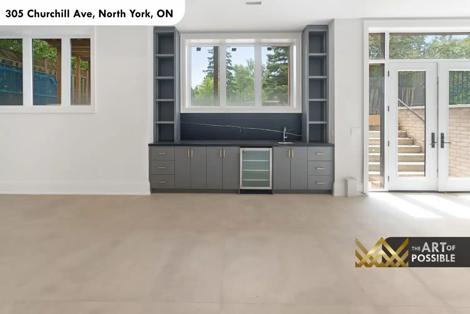 Wet bar close-up with grey shaker cabinets, brass pulls, dark marble slab and built-in beverage cooler