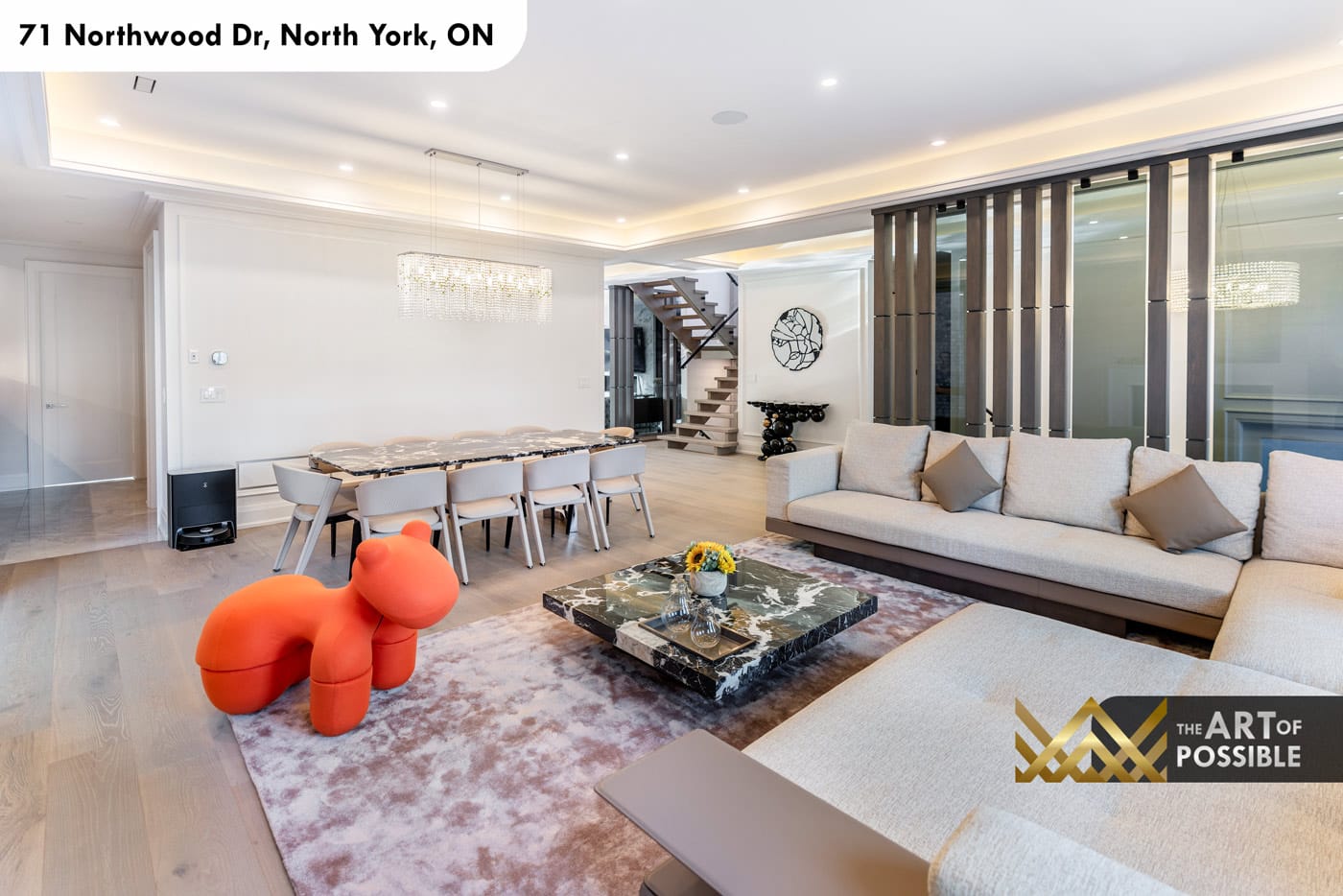 Main floor overview showing living and dining zones, crystal chandelier and glass staircase partition