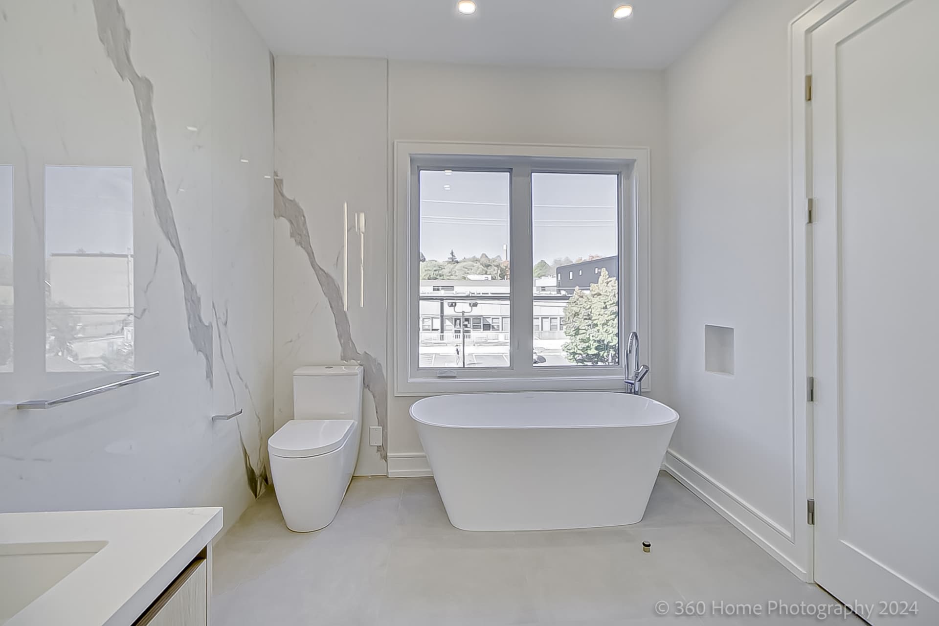 Primary ensuite freestanding soaker tub with marble feature wall at 100 Glenvale Blvd