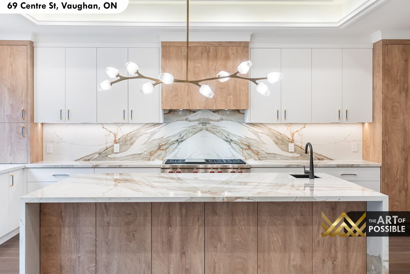 Kitchen island and backsplash detail showing book-matched Calacatta veining and 6-burner range