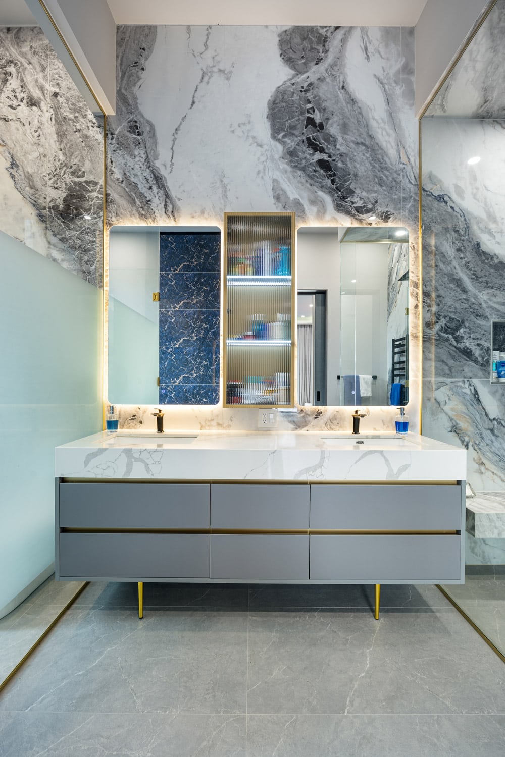 Primary ensuite vanity with grey floating vanity, brass hardware, backlit LED mirror and blue Sodalite marble medicine cabinet
