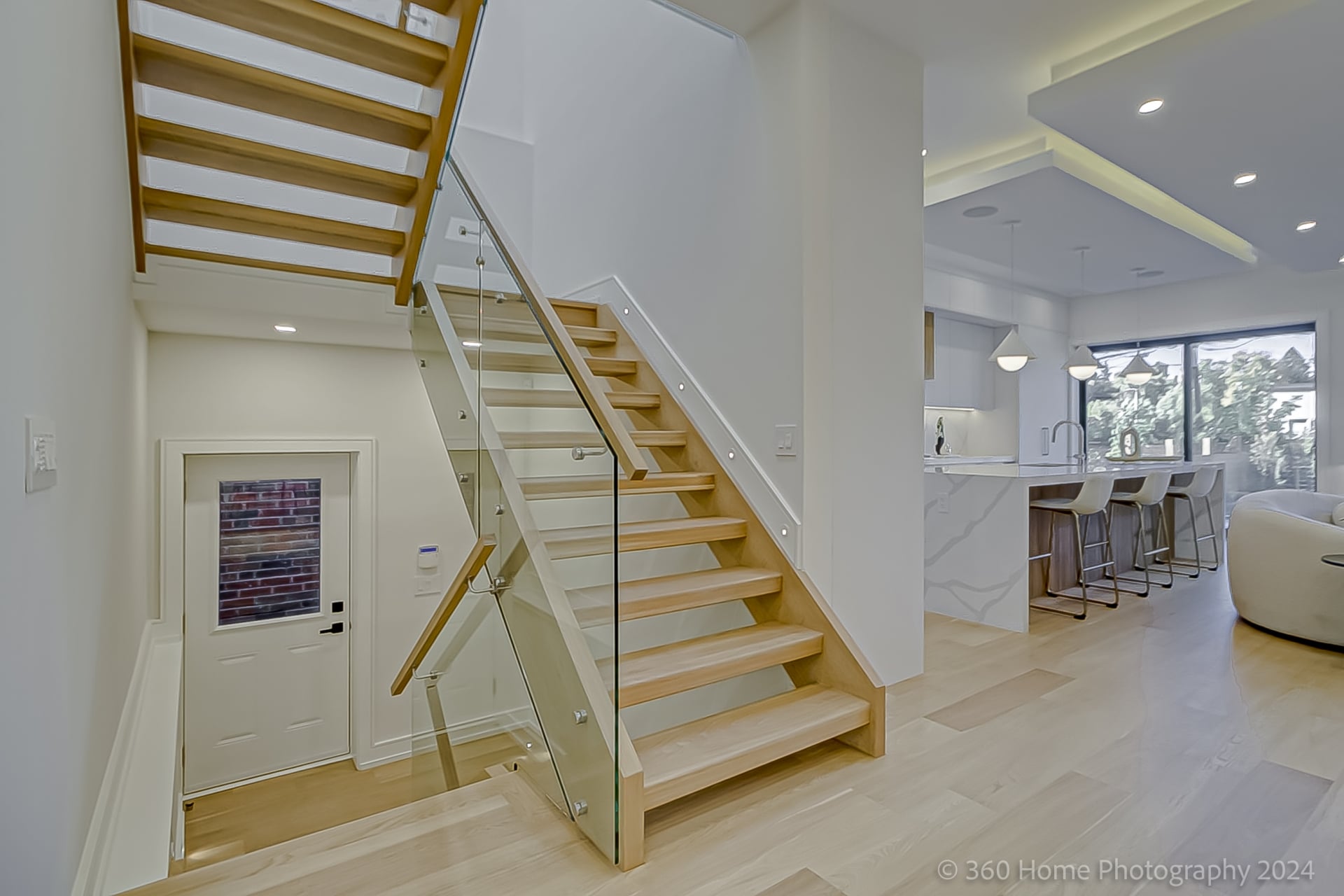 Open-tread oak staircase with frameless glass panel railings at 100 Glenvale Blvd