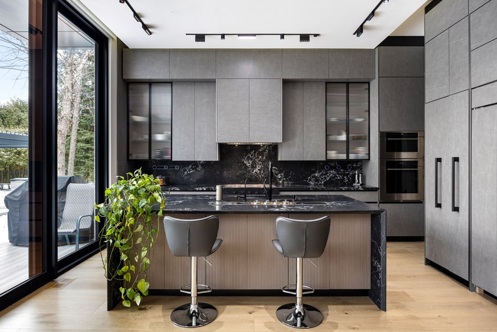 Kitchen at 27 Farr Ave with black marble waterfall island, reeded oak base, grey concrete-look cabinetry and floor-to-ceiling sliding doors to rear yard