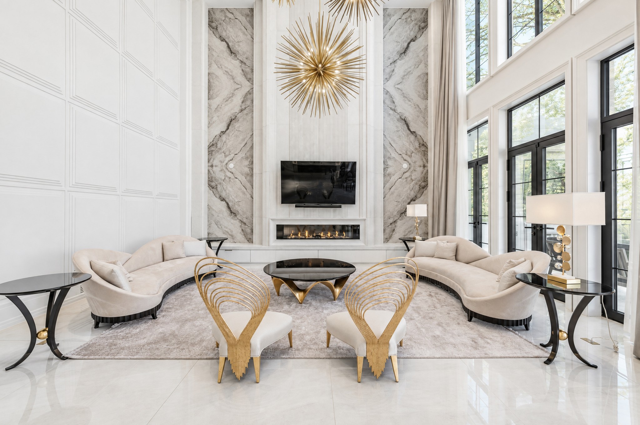 Two-storey family room with book-matched stone fireplace wall and gold starburst chandeliers