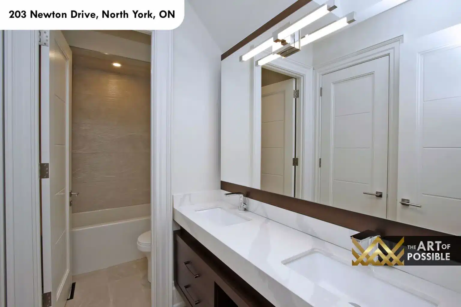 Shared bathroom with dark wood-framed mirror, double vanity and tile tub surround