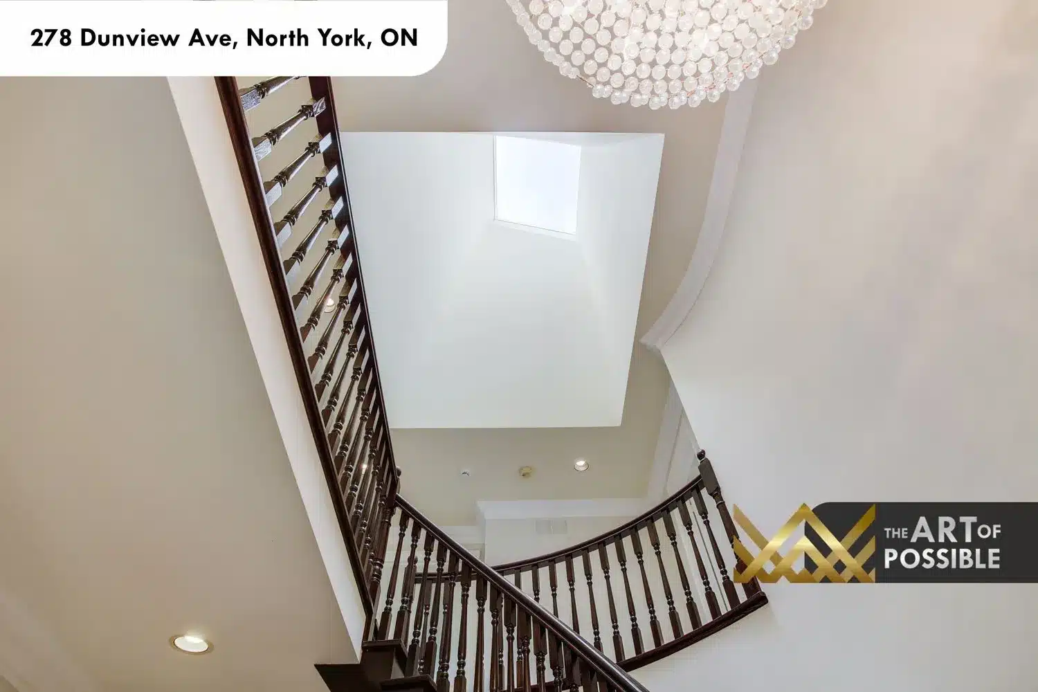 Overhead view of the curved staircase with skylight above and crystal chandelier