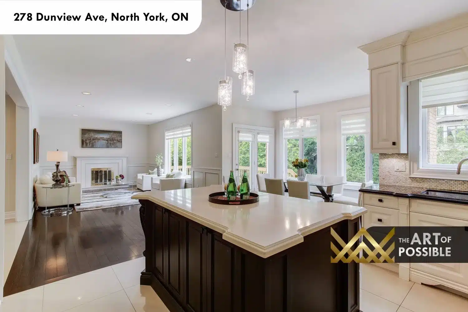 Kitchen island and family room beyond with white fireplace surround and garden views