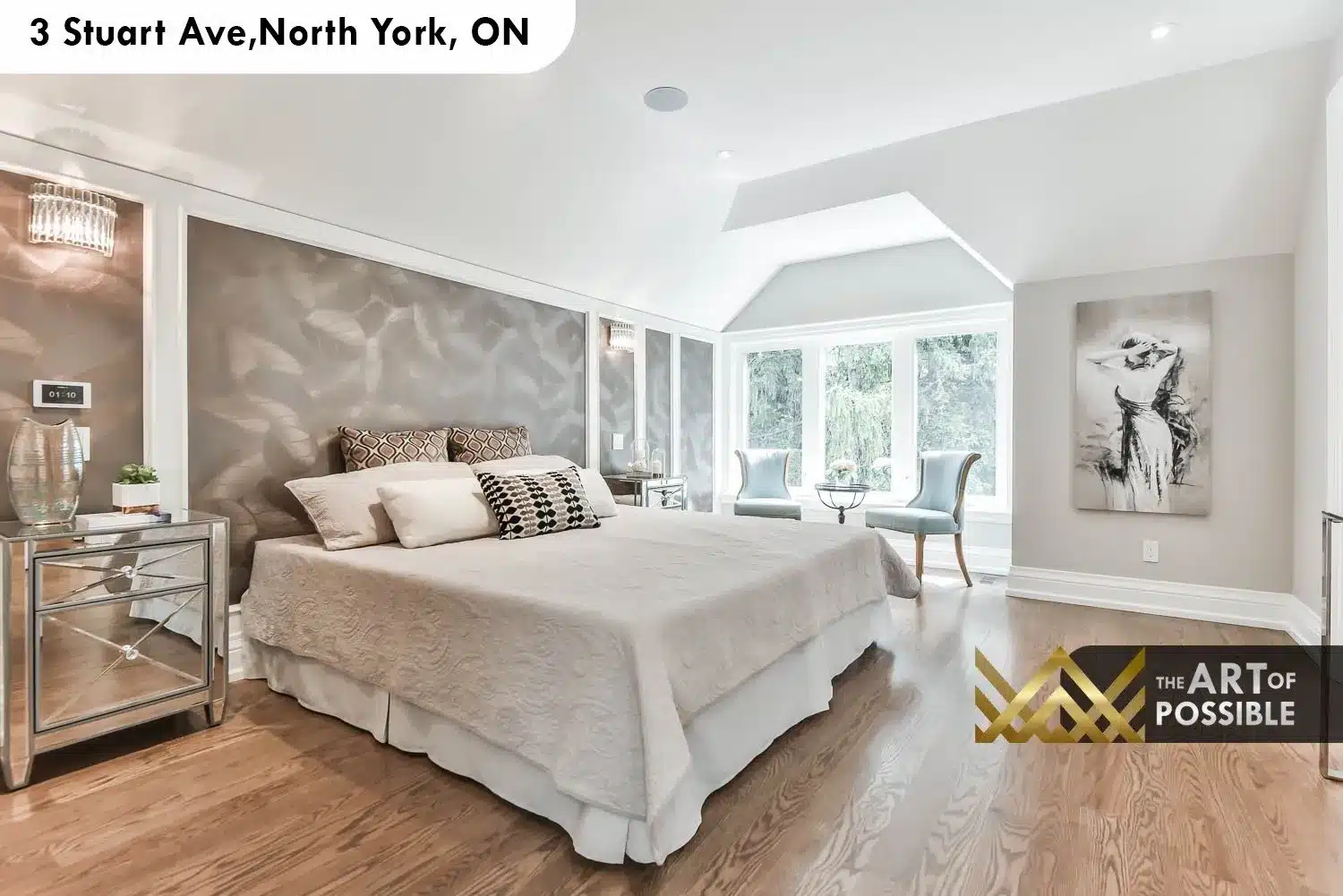 Primary bedroom with vaulted tray ceiling, silver-grey textured accent wall and large rear window seating area