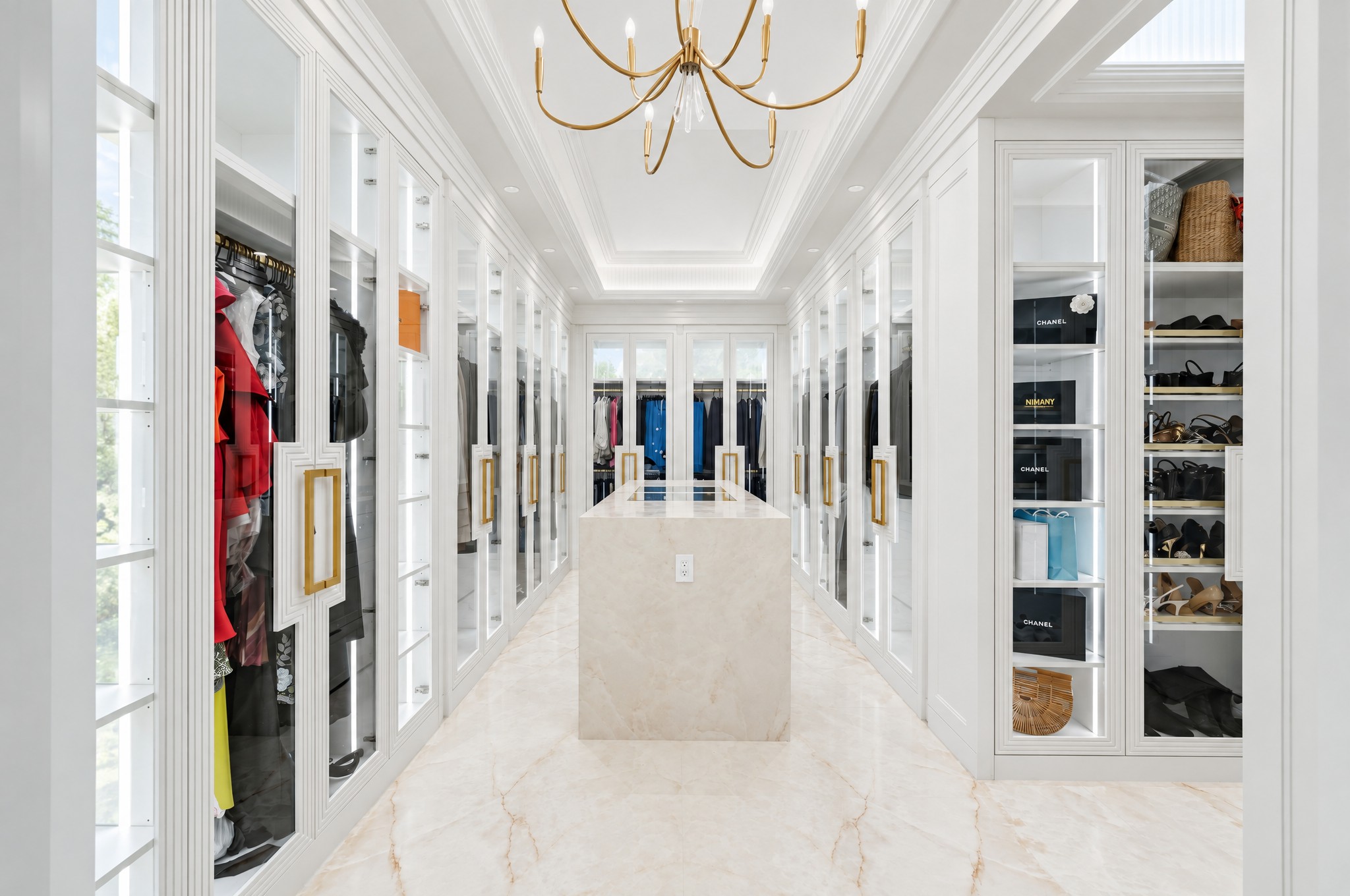 Second dressing room with lit glass wardrobes, stone island and brass chandelier