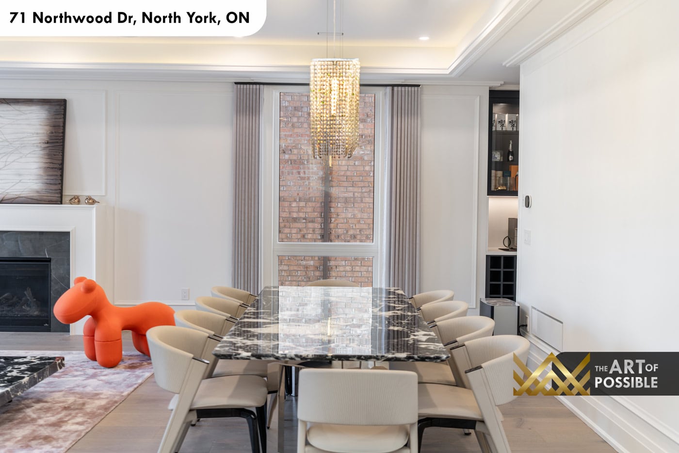 Dining area with rectangular dark marble slab table, crystal pendant and white fireplace surround