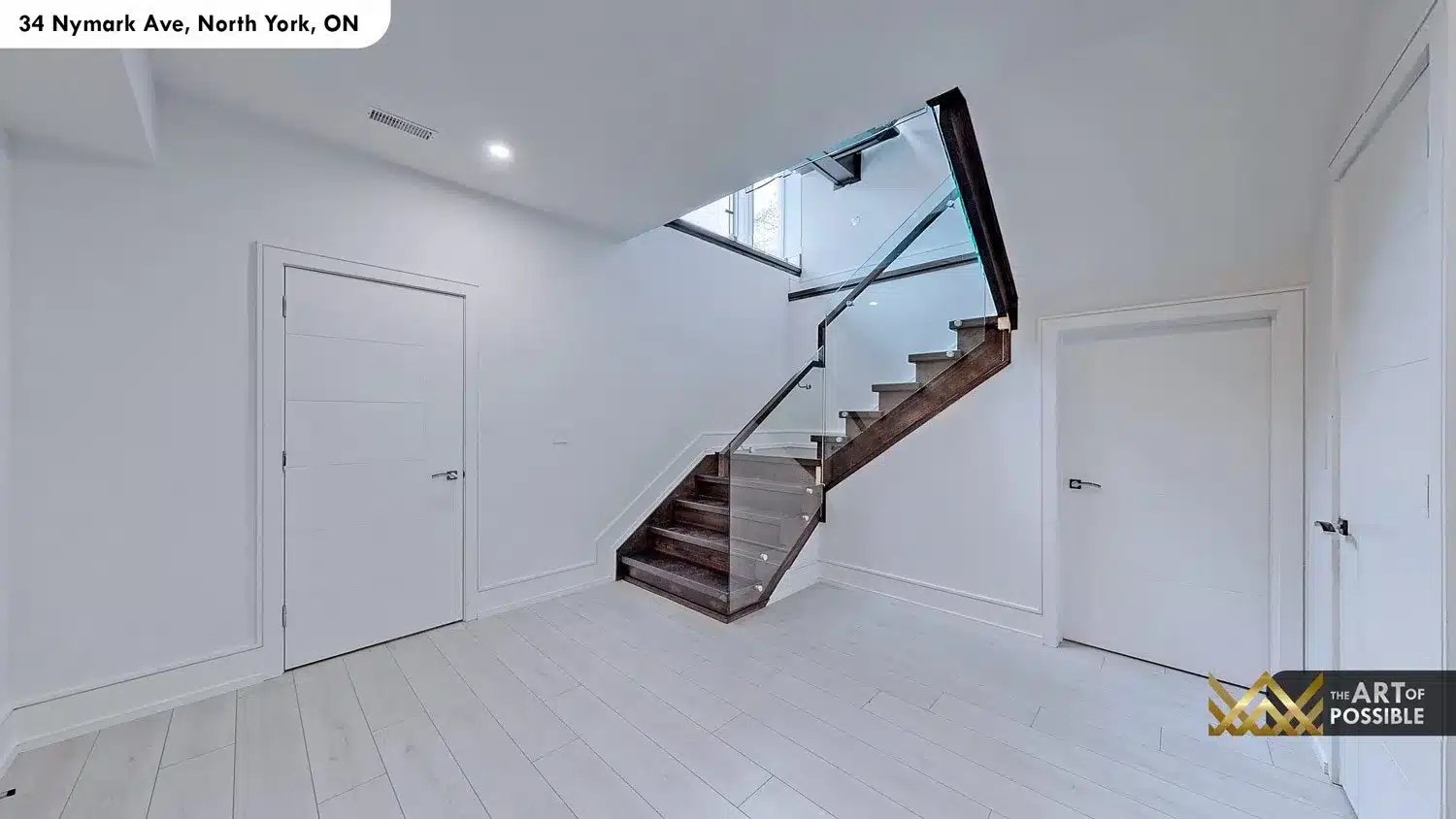 Lower level landing with floating dark wood staircase and frameless glass railing connecting to main floor