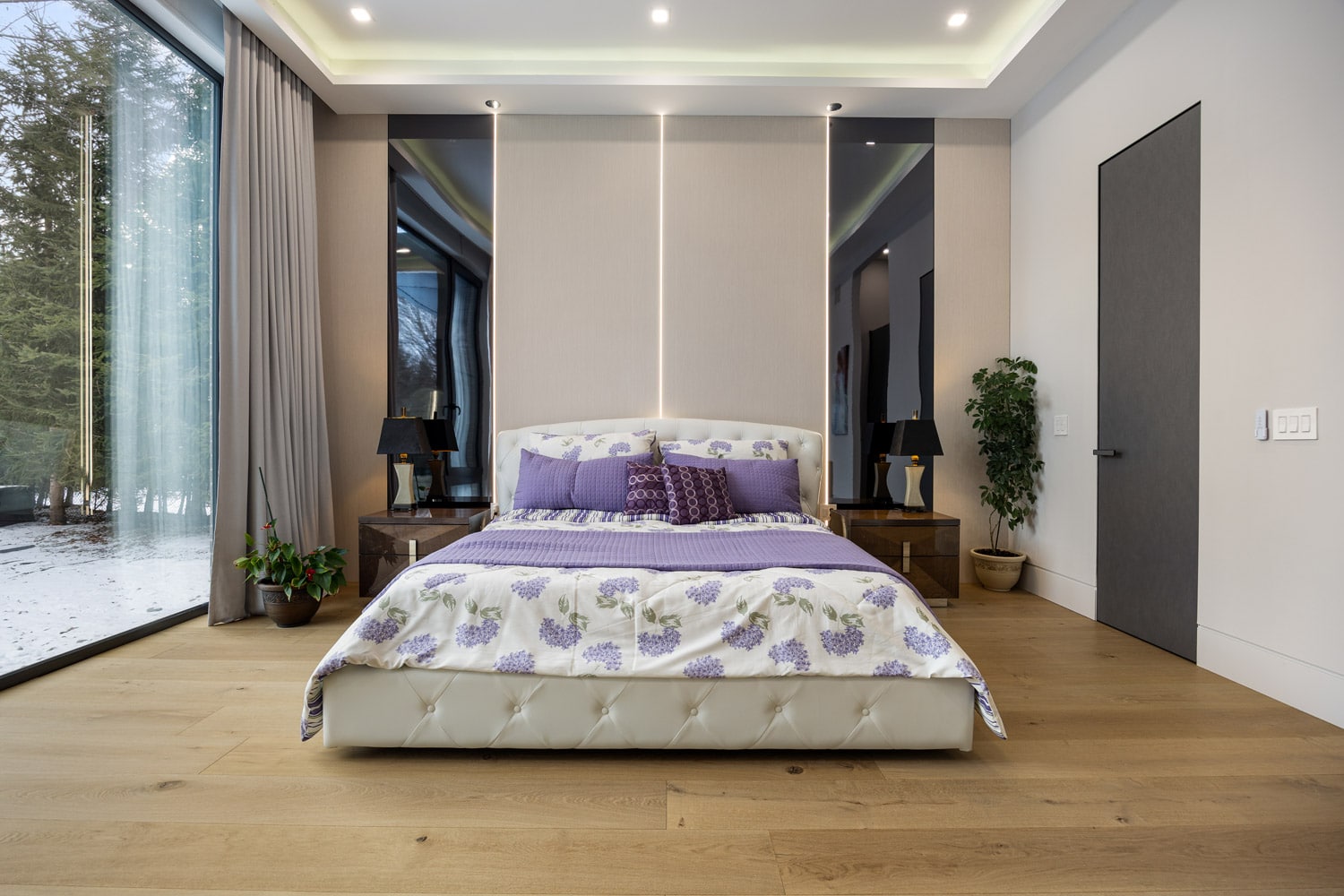 Primary bedroom at 27 Farr Ave with tray ceiling LED lighting, floor-to-ceiling glass doors and mirror panels with LED strip accents flanking headboard