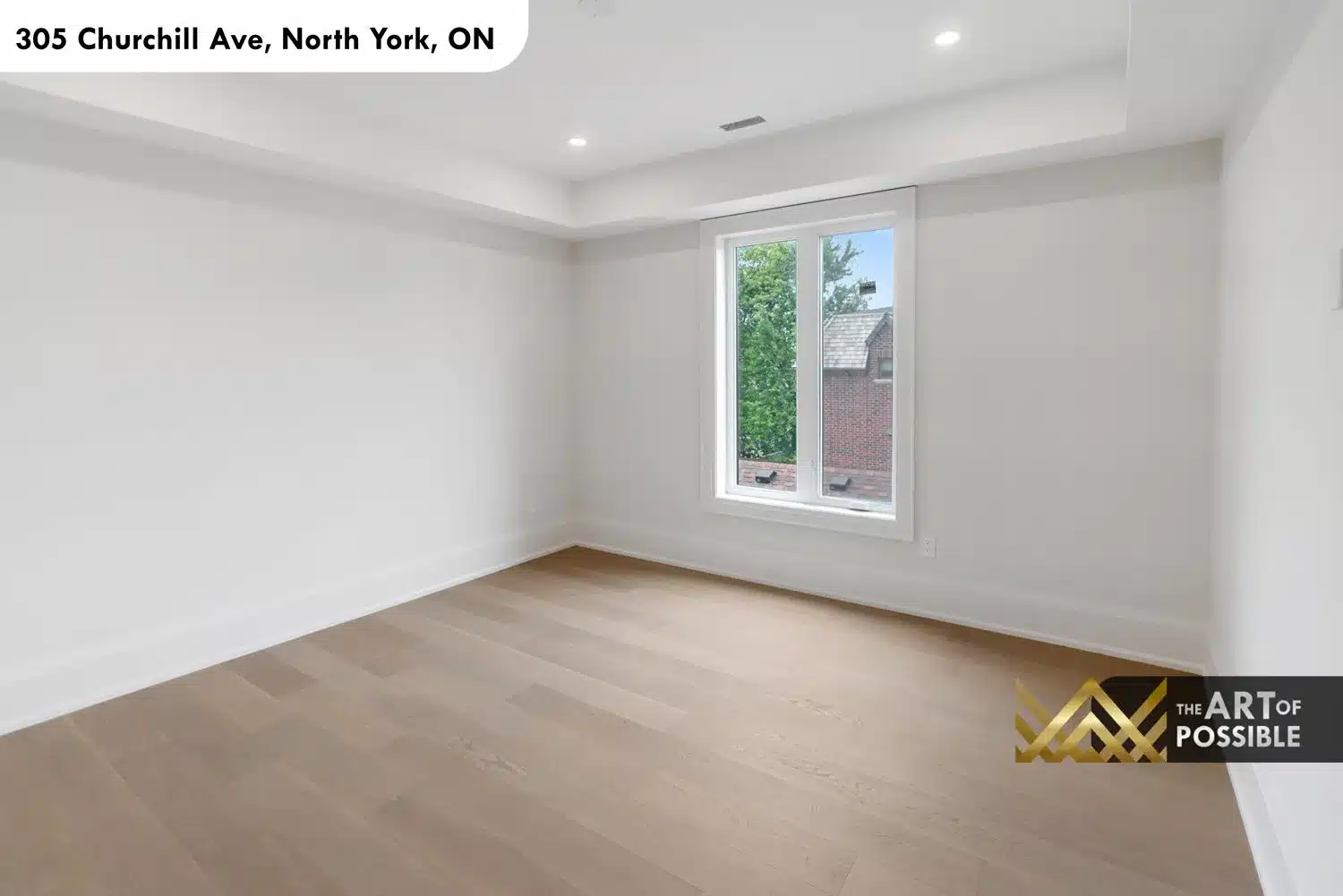 Secondary bedroom with tray ceiling, light oak floors and rear garden window view