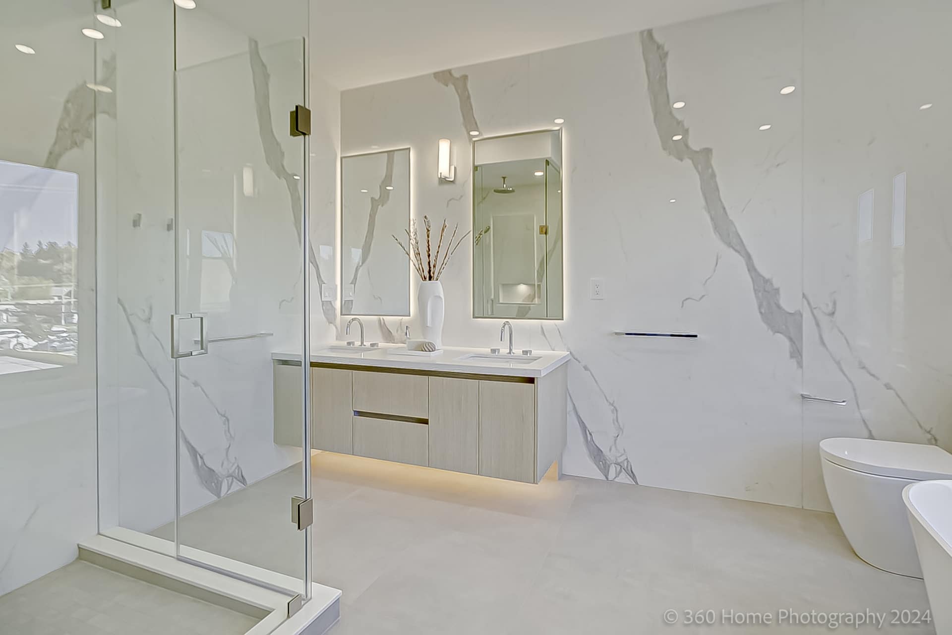 Primary ensuite at 100 Glenvale Blvd with Calacatta marble slab walls, dual oak floating vanity and backlit LED mirrors