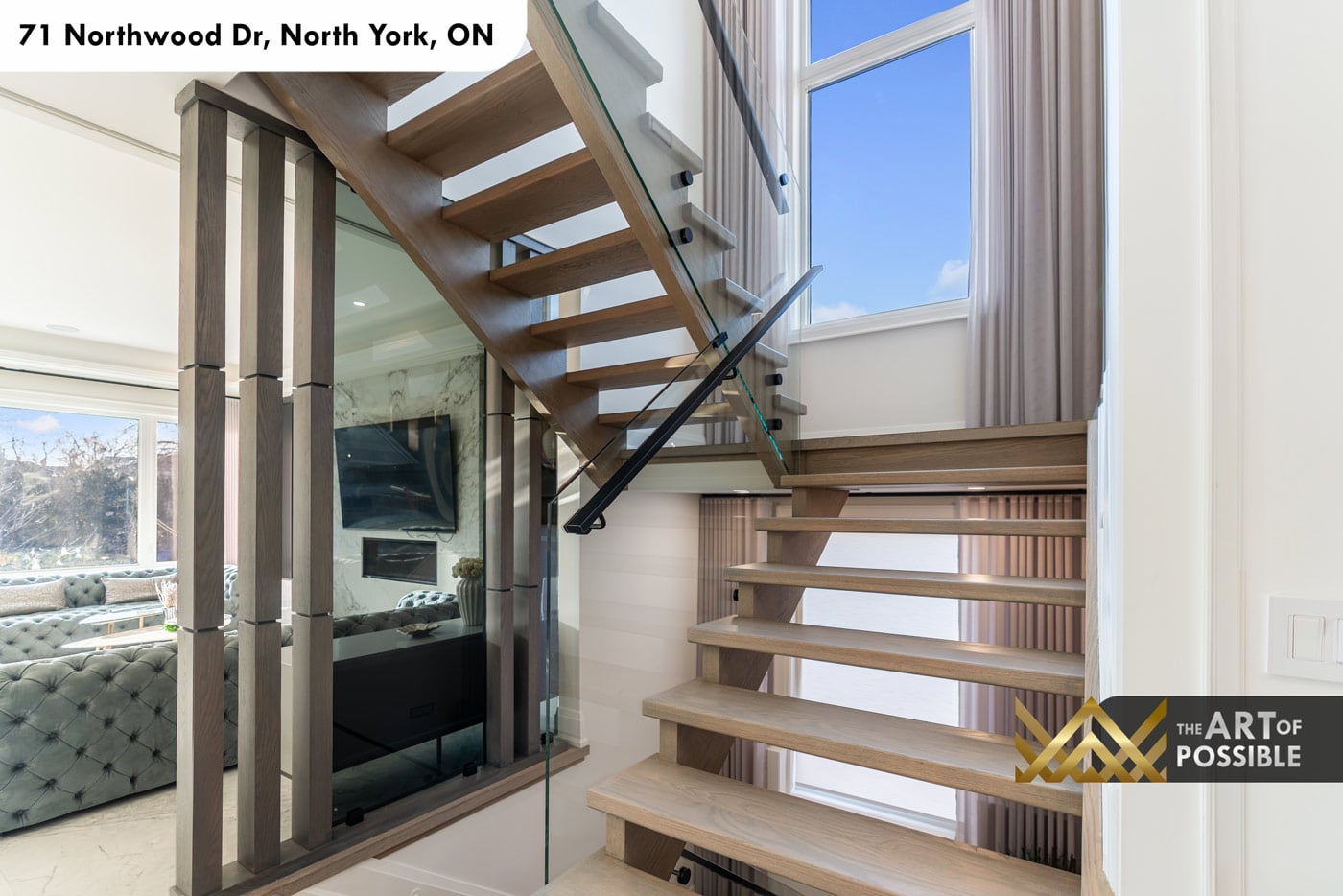 Floating light oak staircase with frameless glass panel railing and matte black hardware