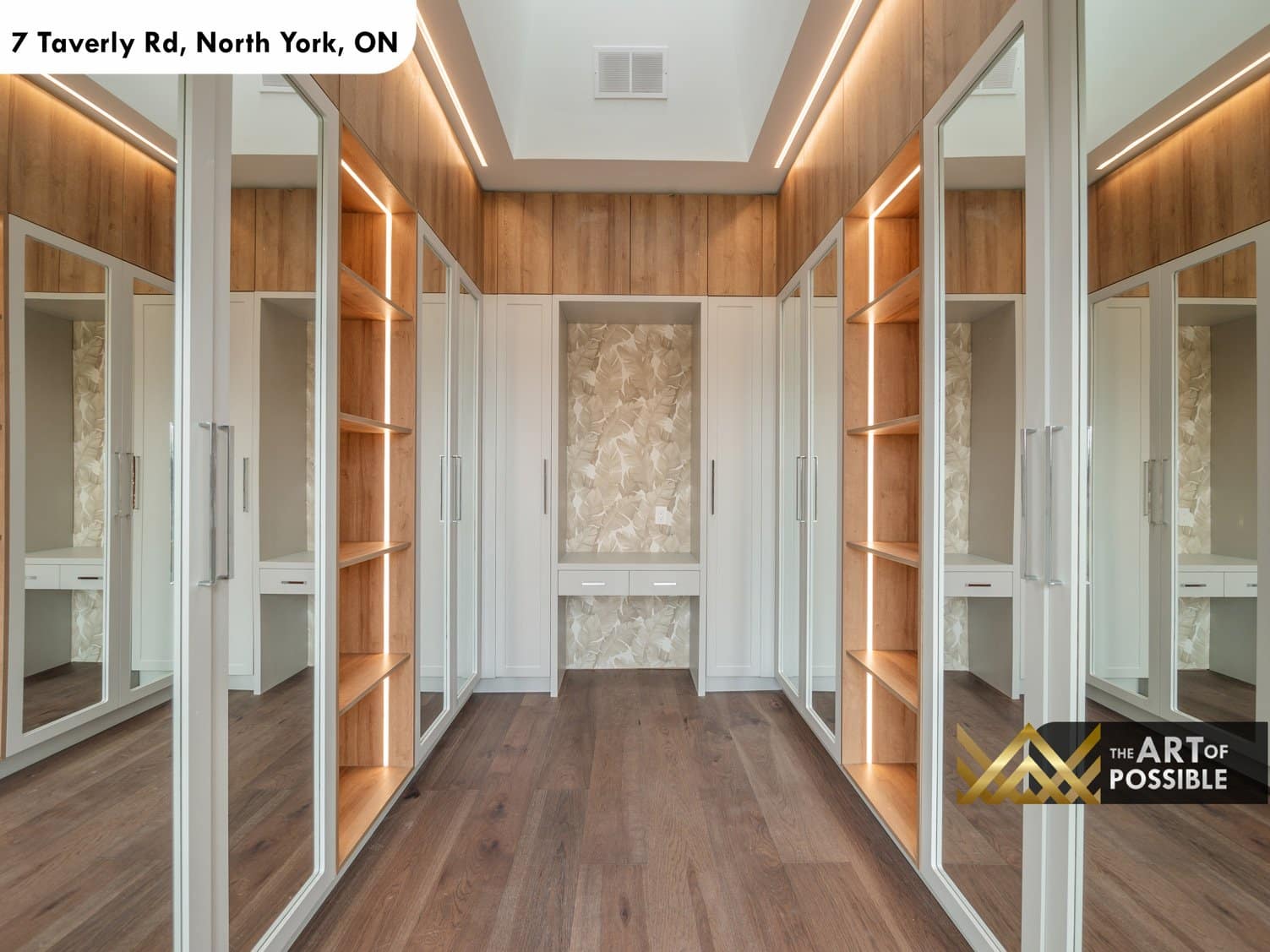 Primary walk-in closet with walnut paneling, mirrored cabinet doors and LED strip lighting